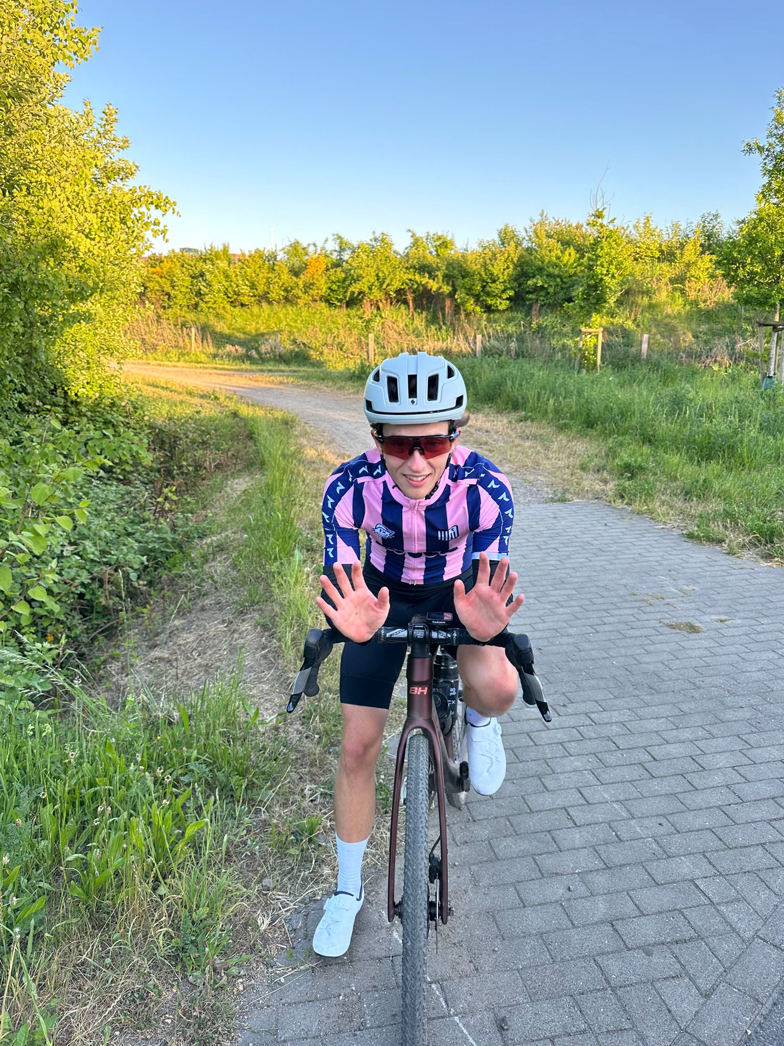 Junger Mann auf Gravelbike in der Natur um Hamburg hebt die Hände zur Begrüßung